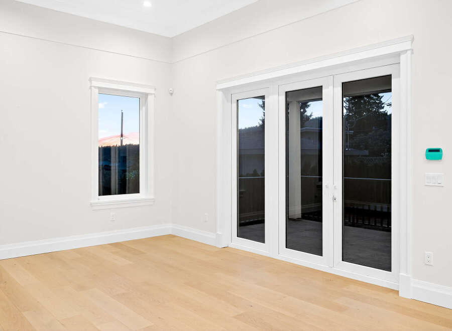This bright and airy room boasts a minimalist design with clean white walls, complemented by warm hardwood flooring.