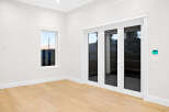 This bright and airy room boasts a minimalist design with clean white walls, complemented by warm hardwood flooring.