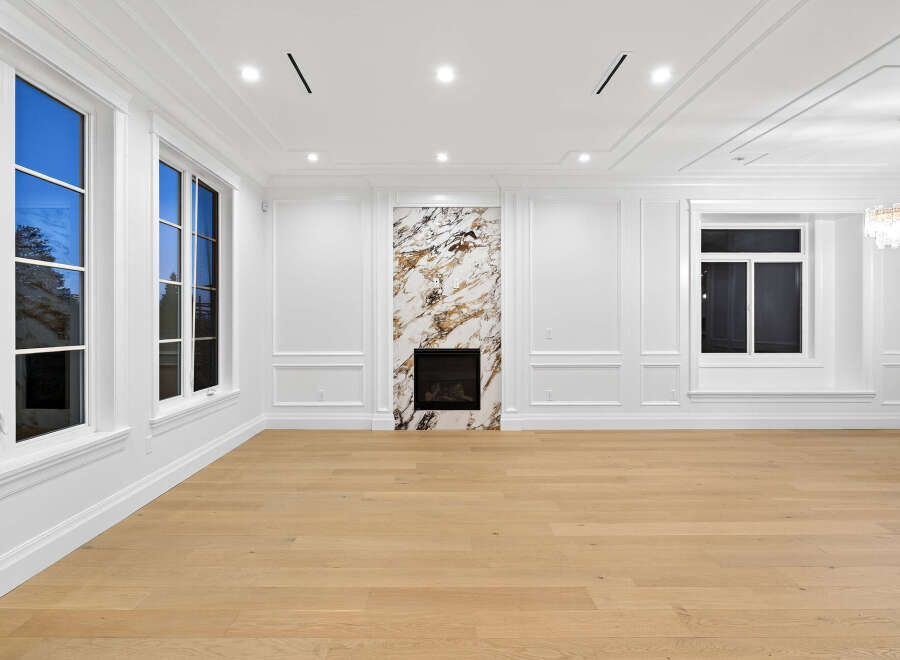 This spacious living room boasts an elegant fireplace with marble surround, complemented by natural light streaming through large windows.