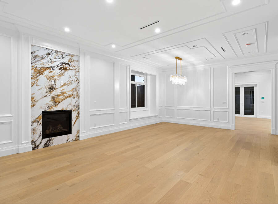 Step into luxury with this stunning living room featuring elegant white wall paneling and a striking marble fireplace.