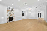 Step into luxury with this stunning living room featuring elegant white wall paneling and a striking marble fireplace.