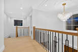 This interior showcases a luxurious hallway with light hardwood floors, leading to a staircase with an elegant black metal railing.