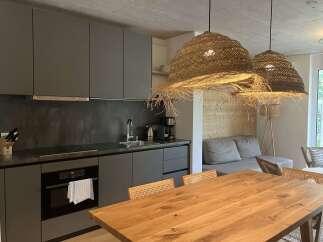 This inviting property boasts a modern kitchen with sleek gray cabinetry and stainless steel appliances, complemented by unique woven light fixtures.
