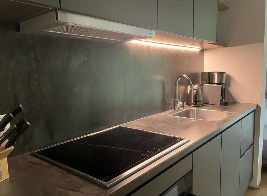 This modern kitchen boasts sleek gray cabinetry, a stainless steel sink, and an integrated cooktop for a clean, minimalist aesthetic.