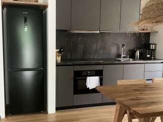This modern kitchen boasts sleek gray cabinetry, a contrasting dark backsplash, and stainless steel appliances, creating a sophisticated culinary space.