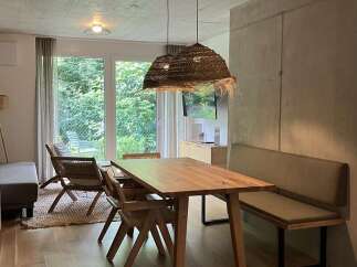 This inviting dining area features a wooden table paired with woven chairs and a comfortable bench, perfect for family meals or entertaining guests.