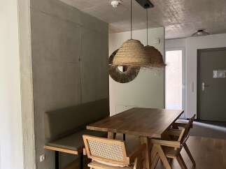 This interior showcases a modern dining area with a wooden table set, complemented by unique straw pendant lights, providing a warm and inviting ambiance.
