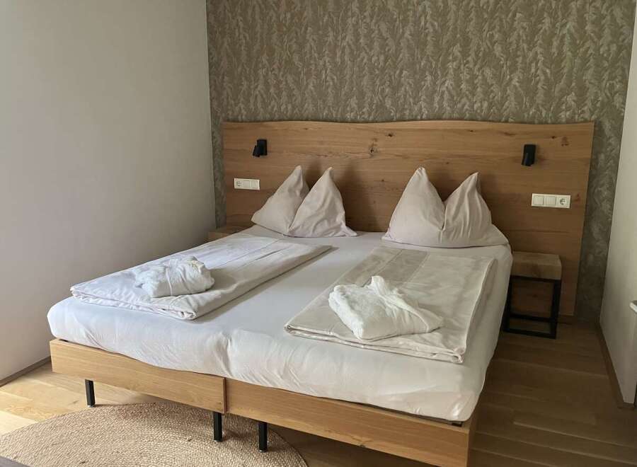 This inviting bedroom features a king-sized bed with a stylish wooden headboard, perfect for a relaxing stay.