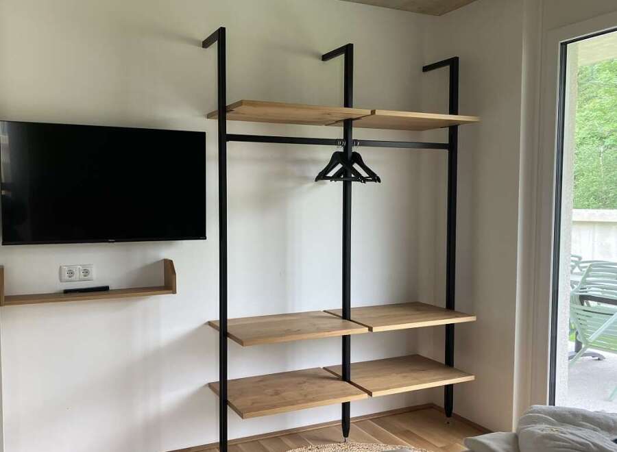 This property features a modern, open-concept closet design with sleek black metal framing and light wood shelving, offering both style and functionality.