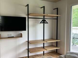 This property features a modern, open-concept closet design with sleek black metal framing and light wood shelving, offering both style and functionality.