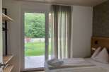 Discover a serene bedroom featuring a seamless indoor-outdoor flow with a large glass door opening to lush greenery.