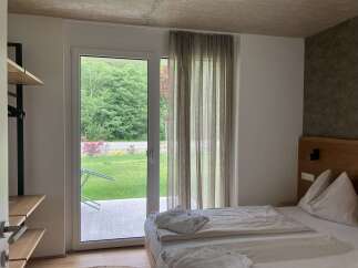 Discover a serene bedroom featuring a seamless indoor-outdoor flow with a large glass door opening to lush greenery.