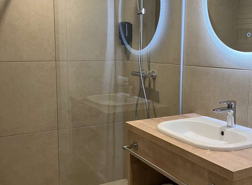 This bathroom features a modern design with a walk-in shower, a sleek vanity with a sink, and ample storage space for towels and toiletries.