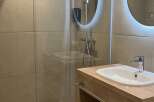 This bathroom features a modern design with a walk-in shower, a sleek vanity with a sink, and ample storage space for towels and toiletries.