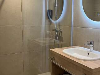 This bathroom features a modern design with a walk-in shower, a sleek vanity with a sink, and ample storage space for towels and toiletries.
