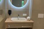 This bathroom features a modern round mirror with LED lighting, providing both style and functionality.