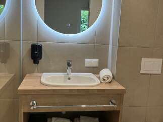 This bathroom features a modern round mirror with LED lighting, providing both style and functionality.