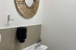 This bathroom features a round woven mirror that adds a touch of natural elegance.