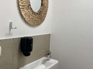 This bathroom features a round woven mirror that adds a touch of natural elegance.