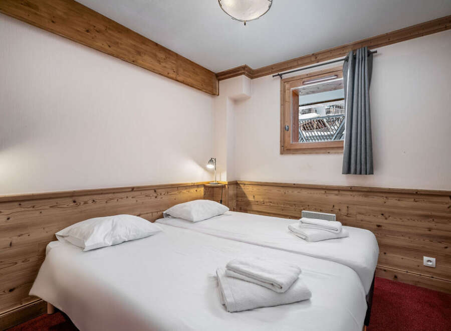 This inviting bedroom features two twin beds with crisp white linens and plush towels, perfect for a cozy stay.