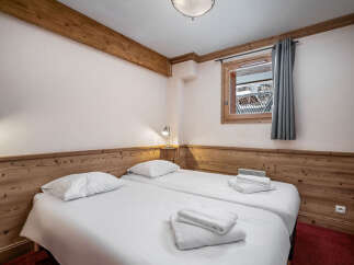This inviting bedroom features two twin beds with crisp white linens and plush towels, perfect for a cozy stay.