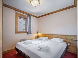 This inviting bedroom features two twin beds with crisp white linens and plush towels, perfect for a relaxing stay.