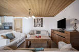 This cozy living room features a warm wood-paneled ceiling, comfortable sofas, and a modern entertainment center.