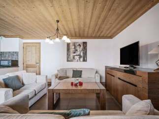 This cozy living room features a warm wood-paneled ceiling, comfortable sofas, and a modern entertainment center.