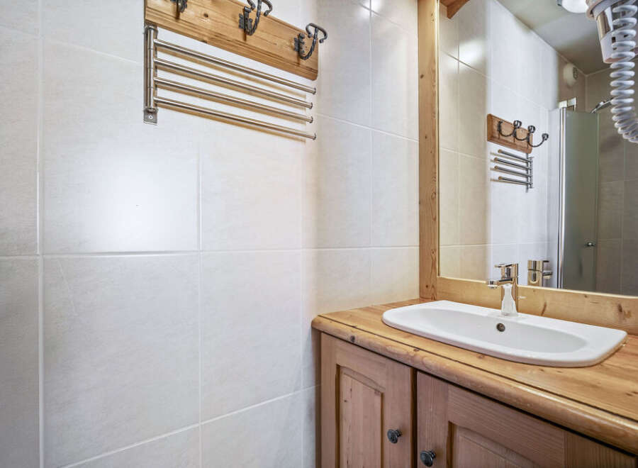 This bathroom features a classic design with white tiled walls and a wooden vanity.