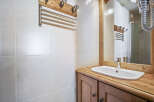 This bathroom features a classic design with white tiled walls and a wooden vanity.