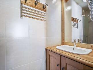 This bathroom features a classic design with white tiled walls and a wooden vanity.