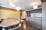 This inviting property features a spacious dining area with a large wooden table and comfortable seating, seamlessly flowing into a modern kitchen equipped with sleek wooden cabinetry and countertops.