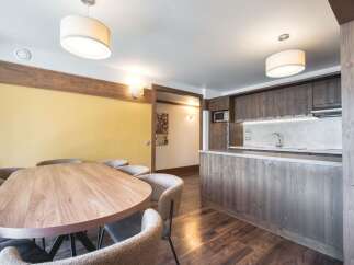 This inviting property features a spacious dining area with a large wooden table and comfortable seating, seamlessly flowing into a modern kitchen equipped with sleek wooden cabinetry and countertops.