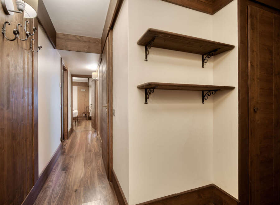 This hallway features beautiful wood accents, including the flooring, doors, shelves, and trim, creating a warm and inviting atmosphere.