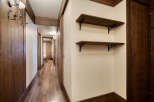 This hallway features beautiful wood accents, including the flooring, doors, shelves, and trim, creating a warm and inviting atmosphere.