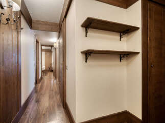 This hallway features beautiful wood accents, including the flooring, doors, shelves, and trim, creating a warm and inviting atmosphere.