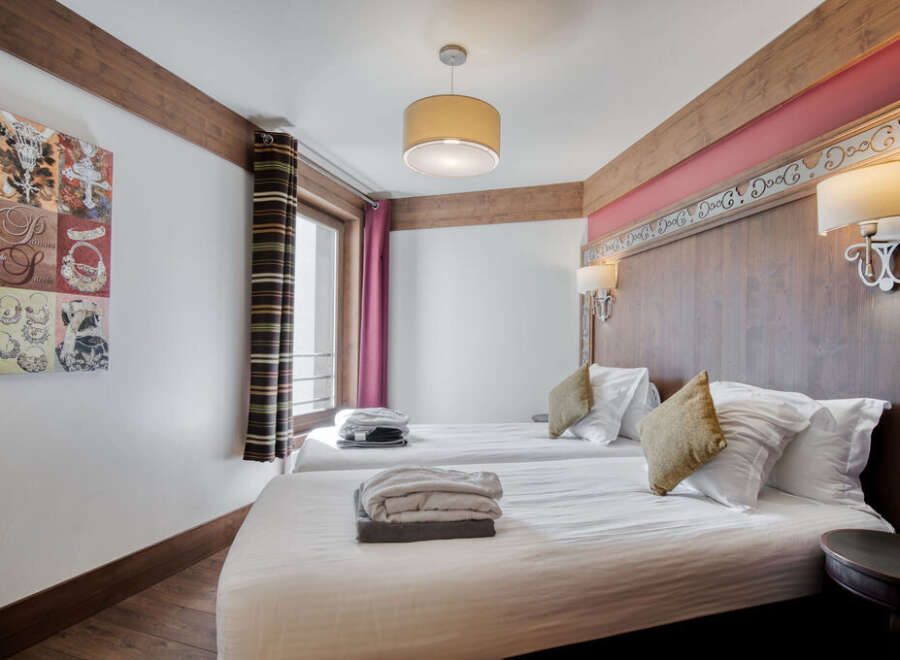 Experience comfort in this inviting bedroom featuring twin beds with crisp white linens and cozy throw pillows.