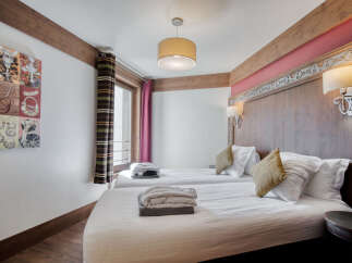 Experience comfort in this inviting bedroom featuring twin beds with crisp white linens and cozy throw pillows.