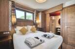 This inviting bedroom features warm wood paneling, creating a cozy, rustic ambiance.