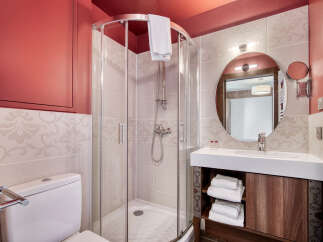 This bathroom features a modern shower with glass enclosure, a sleek vanity with ample storage, and a round mirror that enhances the space.