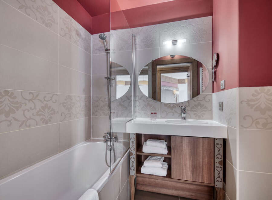 This bathroom features a modern design with a bathtub, shower, sink, and mirror.