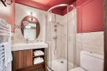 This well-lit bathroom features a modern design with a walk-in shower, a vanity with a round mirror, and a toilet.