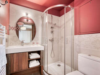 This well-lit bathroom features a modern design with a walk-in shower, a vanity with a round mirror, and a toilet.
