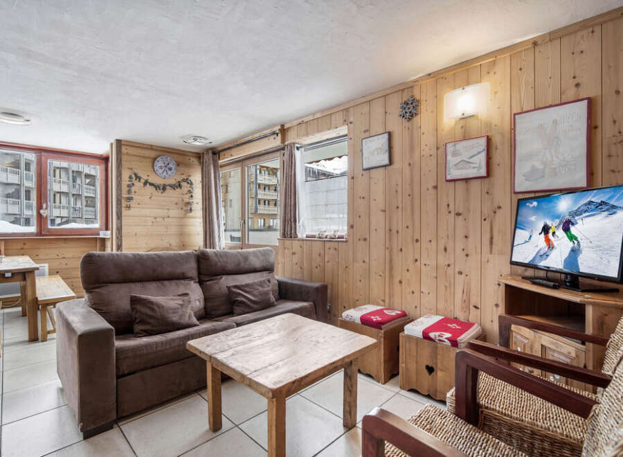 Step into this cozy ski condo featuring wood-paneled walls, a comfortable sofa, and a warm, inviting atmosphere.