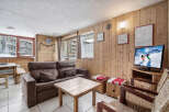 Step into this cozy ski condo featuring wood-paneled walls, a comfortable sofa, and a warm, inviting atmosphere.