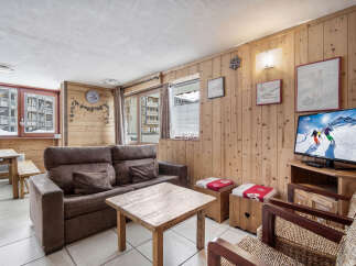 Step into this cozy ski condo featuring wood-paneled walls, a comfortable sofa, and a warm, inviting atmosphere.