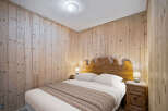 Cozy bedroom featuring wooden walls and a rustic wooden headboard, creating a warm and inviting atmosphere.