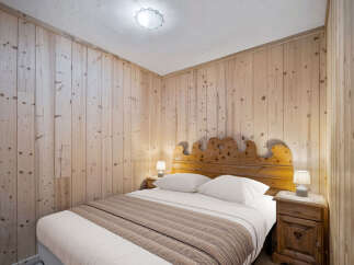 Cozy bedroom featuring wooden walls and a rustic wooden headboard, creating a warm and inviting atmosphere.