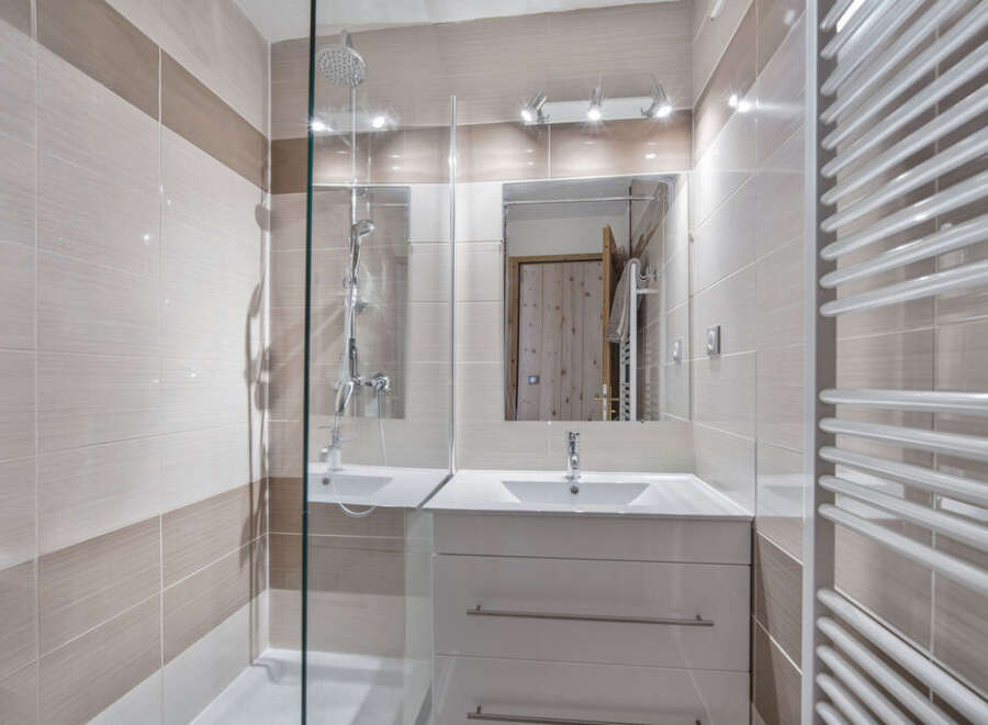 This modern bathroom features stylish beige and white tiling, creating a warm and inviting atmosphere.
