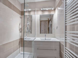 This modern bathroom features stylish beige and white tiling, creating a warm and inviting atmosphere.